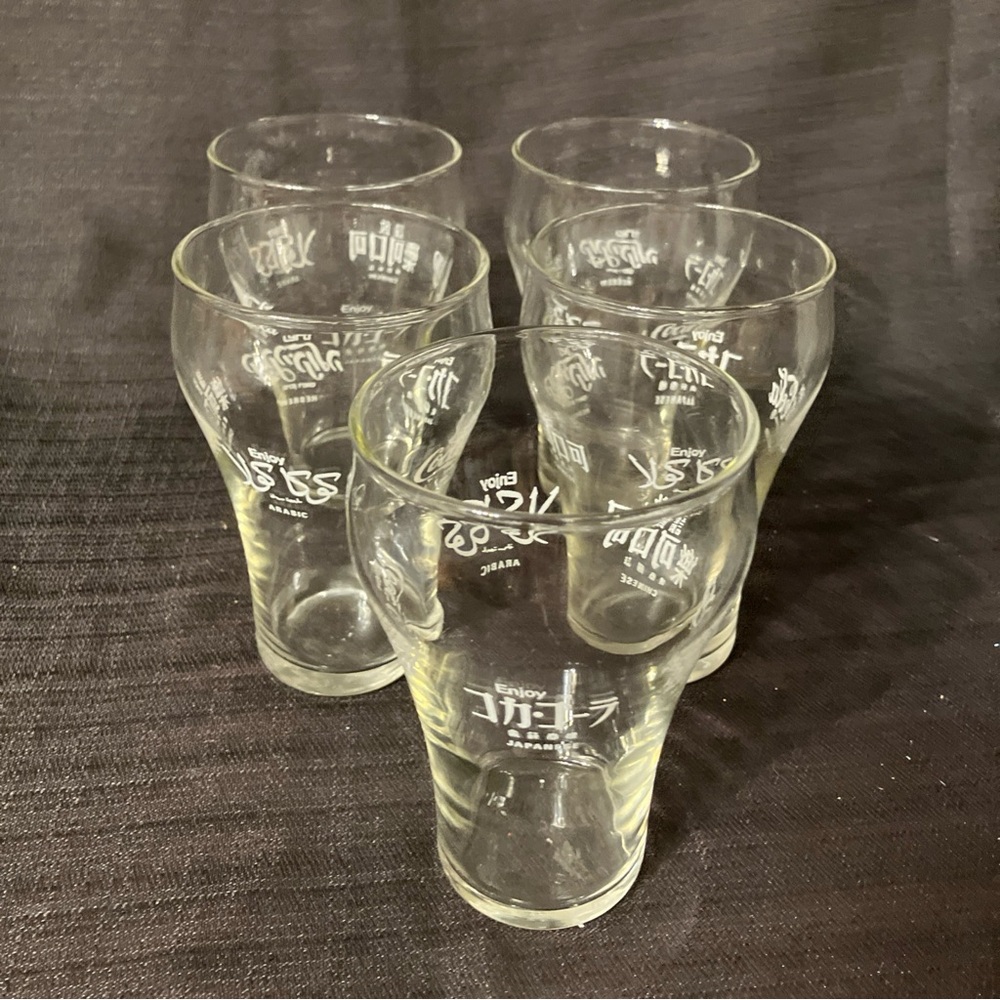 A lot of five Coca-Cola glasses written in five different languages